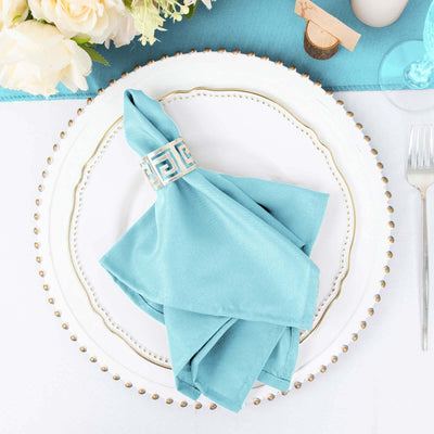 Elegant turquoise napkin with decorative ring on a white plate.