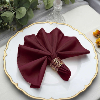 Burgundy cloth napkin elegantly folded on a decorative plate.