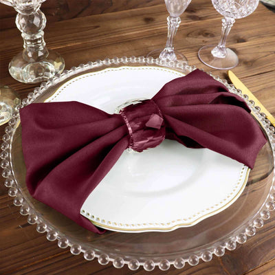 Elegant burgundy napkin tied in a bow on a decorative plate.