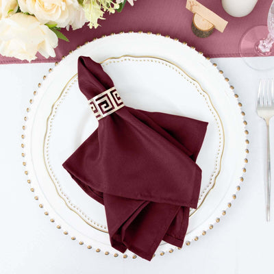 Burgundy napkin elegantly folded on a decorative plate with a gold trim.