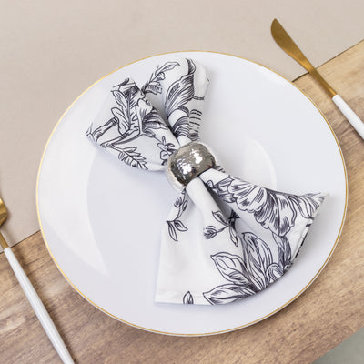 Floral patterned napkin with a silver ring on a white plate