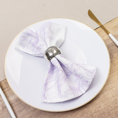 Purple floral napkin with silver ring on a white plate.