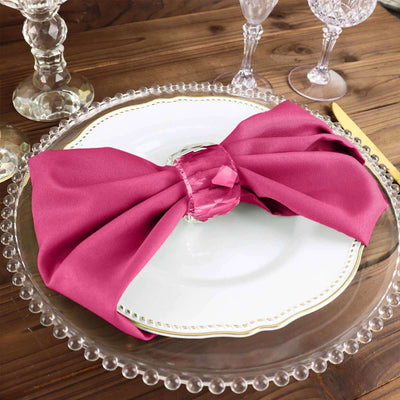 Elegant magenta napkin tied in a bow on a decorative dinner plate.