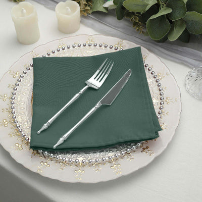 Elegant green napkin with silver cutlery on a decorative plate.