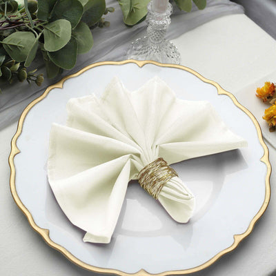 Elegant white napkin folded on a decorative plate with a gold rim.