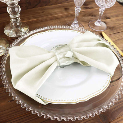 Elegant light green napkin tied with a glass ring on a decorative plate.
