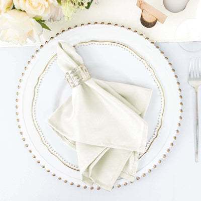 Elegant light green napkin on a decorative plate with a silver napkin ring.
