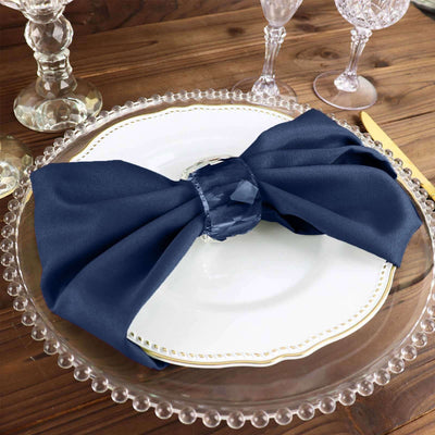 Navy blue napkin elegantly tied on a white plate with crystal glassware in the background.