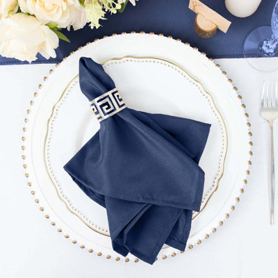 Navy napkin with decorative ring on elegant dinner plate setting.