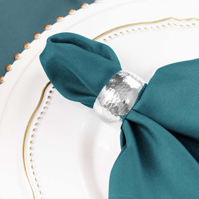 Teal napkin with silver hammered napkin ring on a white plate
