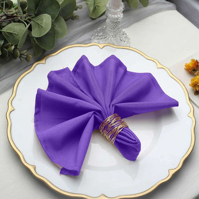 Purple fabric napkin elegantly folded on a decorative plate.