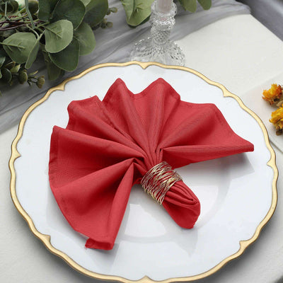 Red fabric napkin elegantly arranged on a decorative plate.