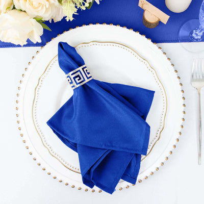 Elegant blue napkin with Greek key design on a decorative white plate.