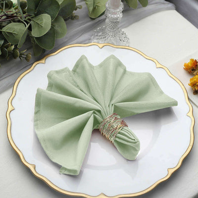 Green fabric napkin elegantly rolled on a decorative plate.