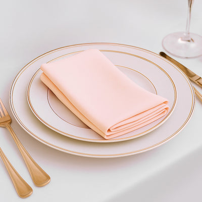 Pink napkin folded on elegant dinner plate with gold trim.
