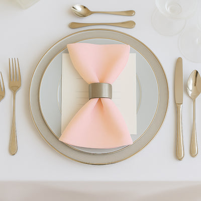 Elegant pink napkin with silver ring on a styled dinner plate setting.
