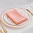 Elegant pink napkin neatly folded on a white plate with gold trim.