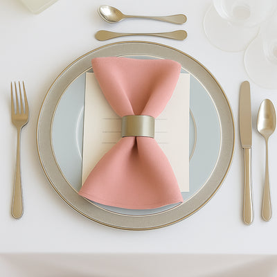 Elegant table setting with pink napkin and silver cutlery.