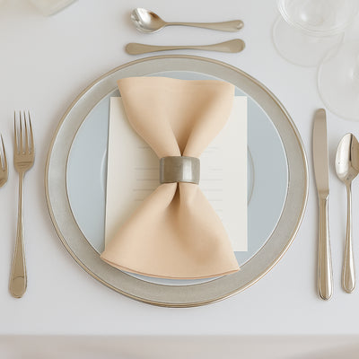 Elegant dinner setting with a beige napkin and silver accents on a plate.
