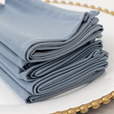 Stack of elegant blue napkins neatly arranged on a decorative plate.