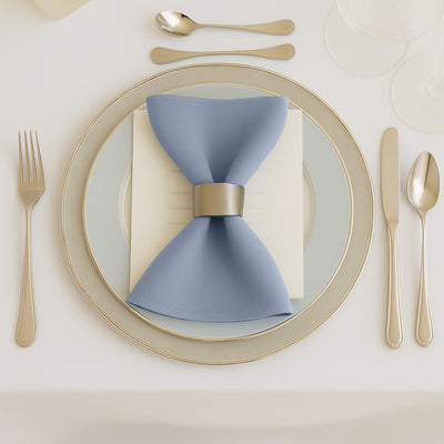 Elegant blue napkin with a silver ring on a beautifully set dinner plate.