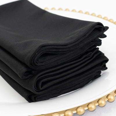 Folded black napkins stacked neatly on a decorative plate.