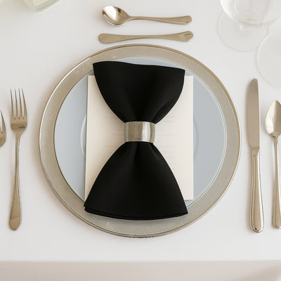 Elegant black napkin with silver ring on a fine dining plate setting.