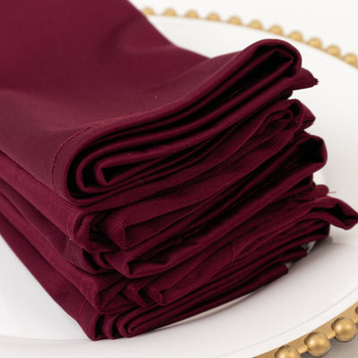 Burgundy folded fabric stacked neatly on a plate.