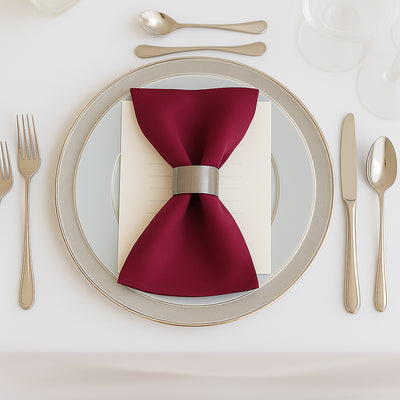 Elegant burgundy napkin with a silver ring on a stylish dinner plate.