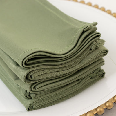 Stack of olive green fabric napkins neatly folded on a white plate.