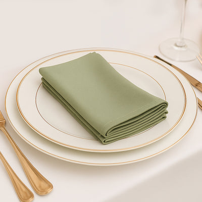 Green napkin neatly folded on a white plate with gold trim.