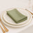 Green napkin neatly folded on a white plate with gold trim.