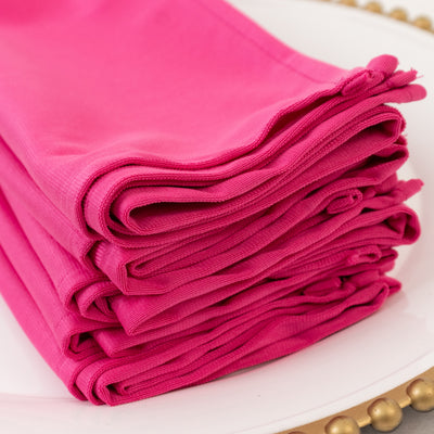 Stack of vibrant pink napkins neatly folded on a decorative plate.