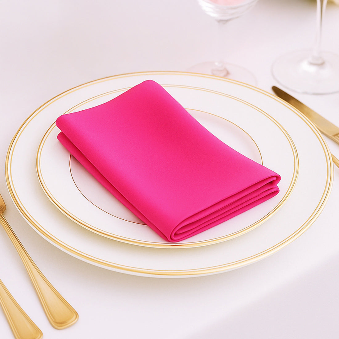 Pink napkin elegantly folded on a white plate with gold trim.