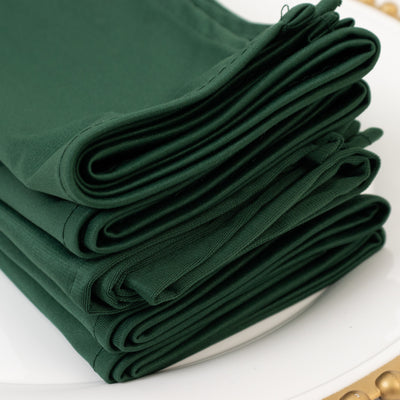 Stack of folded dark green napkins on a white plate.