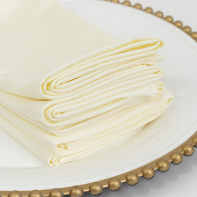 Folded cream napkins stacked on a decorative plate.