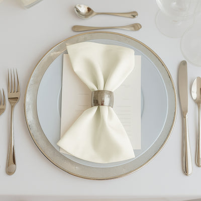 Elegant table setting with a folded napkin and menu on a decorative plate.