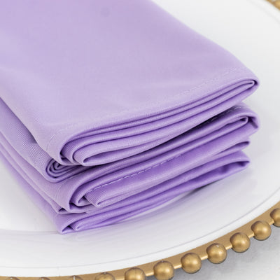 Folded purple fabric napkins stacked on a white plate.