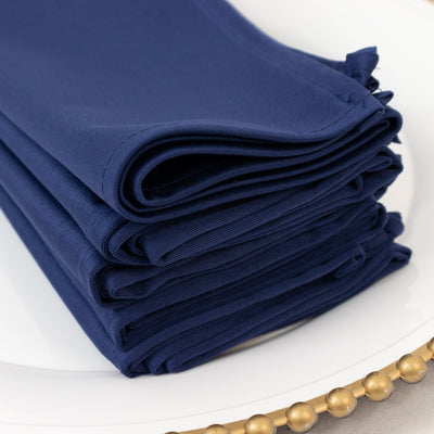 Navy fabric napkins neatly stacked on a decorative plate.