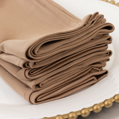 Stack of folded beige napkins on a decorative plate.