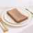 Elegant beige napkin neatly folded on a fine dining plate setting.