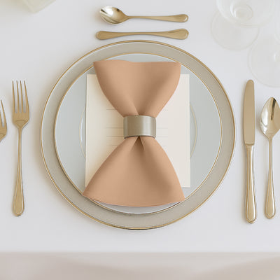 Elegant table setting with a peach napkin and silver ring on a fine china plate.
