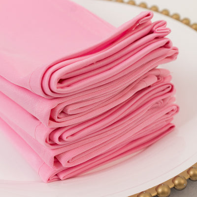 Stack of folded pink napkins on a decorative plate.