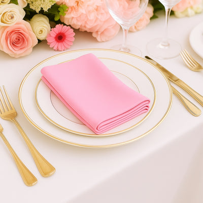 Pink napkin on a gold-rimmed plate, set for an elegant dining experience.