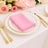 Pink napkin on a gold-rimmed plate, set for an elegant dining experience.