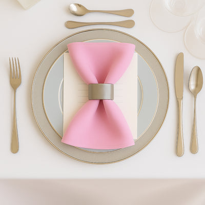 Elegant pink napkin with a silver napkin ring on a decorative plate setting.