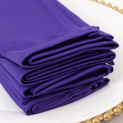 Folded purple fabric napkins stacked neatly on a plate.