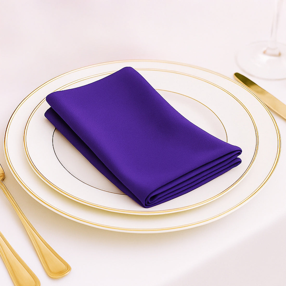 Purple satin napkin neatly folded on an elegant plate with gold trim.