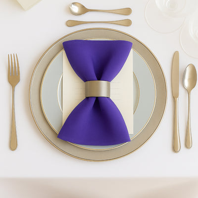Elegant purple bow tie napkin on a stylish dinner plate setting.