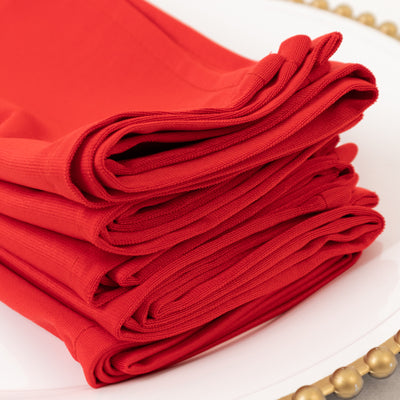 Stack of vibrant red cloth napkins on a decorative plate.